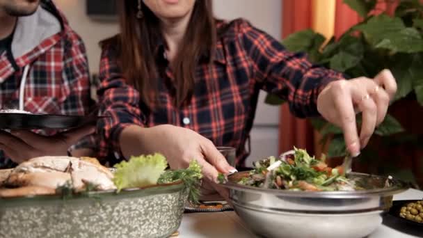 Η σύζυγος και η σύζυγος κάθεται στην κουζίνα στο τραπέζι, η γυναίκα βάζει ένα λαχανικό σαλάτα στο πιάτο τους συζύγους. Τροφίμων — Αρχείο Βίντεο