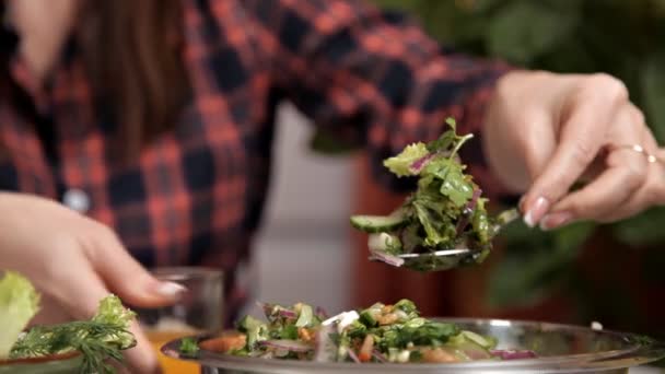 Le mari et la femme sont assis dans la cuisine à la table, la femme met la salade de légumes sur l'assiette des maris. nourriture, maïs — Video