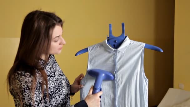 Chica joven acariciando su blusa con una plancha de vapor vertical en casa — Vídeos de Stock