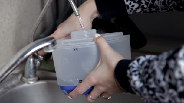 A lány gyűjt víz egy műanyag tartályban tervezett gőzölős vasaló, gőzölő — Stock videók
