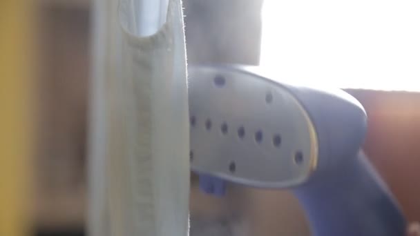 A woman uses steam to iron her blouse. The process of steaming the blouse using a steam cleaner. Close up — Stock Video