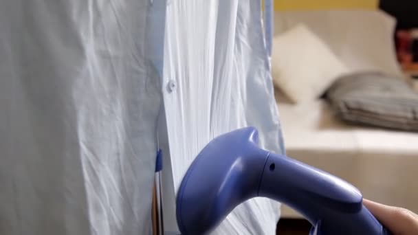 Flickan använder en ångbåt för kläder att räta upp blusen. Processen av ångande kläder närbild — Stockvideo
