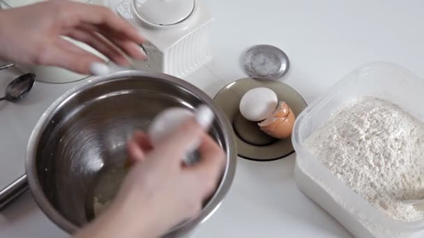 Dívka rozbije vajíčko a přidá do mísy mouku, míchání všechny ingredience — Stock video