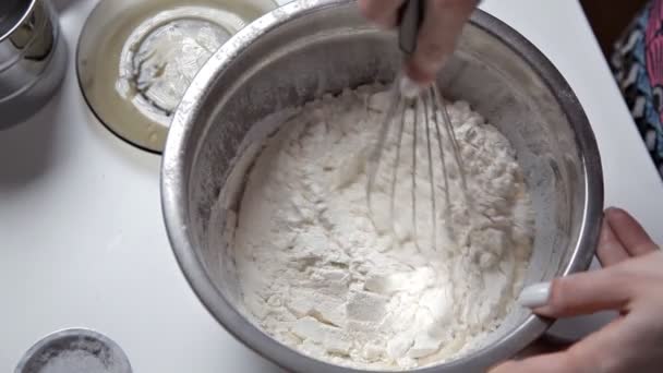 The girl in the kitchen shakes in a silver bowl the necessary ingredients for baking. The concept of cooking and baking — Stock Video