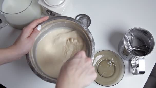 The girl in the kitchen interferes with the milk mass from the dough whisk — Stock Video