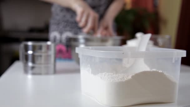 En kvinna häller mjölk från en kopp i en skål med degen. Flickan förbereder pannkakor, cookies, degen — Stockvideo