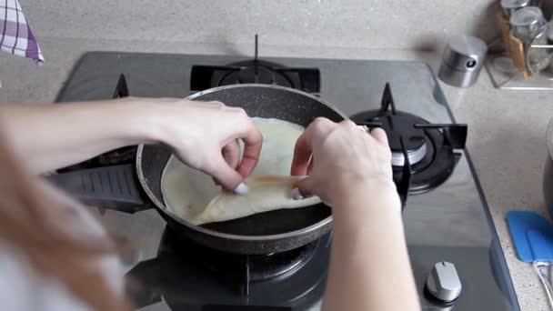 Женщина готовит блинчики, выливает тесто на горячую сковородку. Праздничная Масленица — стоковое видео