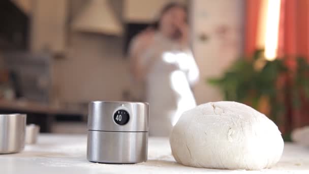 Une jeune fille dans la cuisine a préparé la pâte pour la cuisson. Le fric sur la table, la fille parle au téléphone — Video