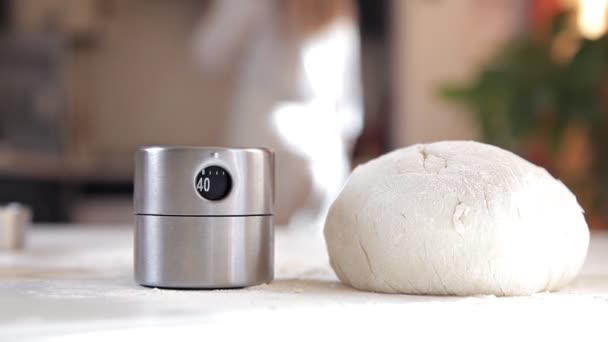 Une jeune fille dans la cuisine a préparé la pâte pour la cuisson. Pâte sur la table, minuterie pour le test — Video