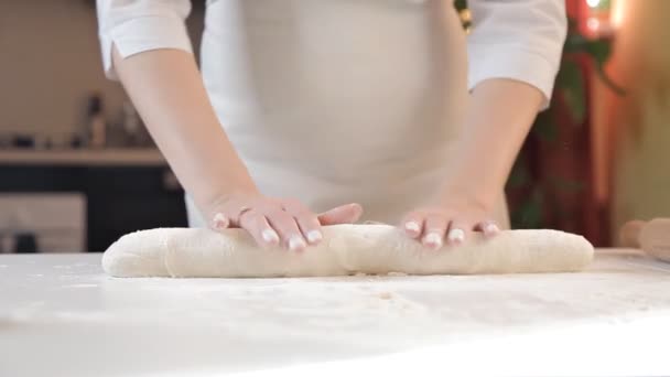Девушка катит свежее тесто по столу булавкой — стоковое видео