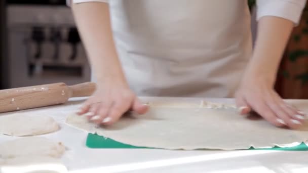 Девушка разглаживает тесто, положив руки на стол, чтобы убедиться, что оно ровное. — стоковое видео