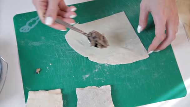 Girl in an apron preparing envelopes with mushrooms for baking at home. — Stock Video