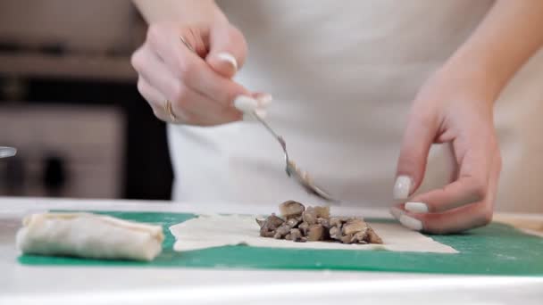 Chica en un delantal preparando sobres con setas para hornear en casa . — Vídeos de Stock