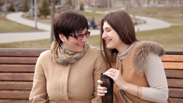 Mor och vuxen dotter tillbringar tid tillsammans utomhus i parken, chattar och skrattar — Stockvideo