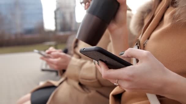 Madre e hija sentadas en el parque y usando el teléfono móvil para escribir mensajes SMS — Vídeos de Stock