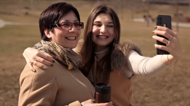 Madre e hija adulta se toman selfies en el parque en verano se vuelve loco y ríe. Emociones felices y positivas.Padres y adolescentes — Vídeo de stock