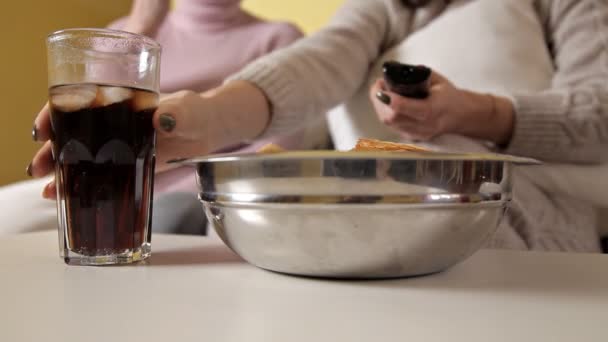 Young girl with her mom at home on the couch watching TV and eating chips and drinking cola. Evening. House. Comfort — Stock Video