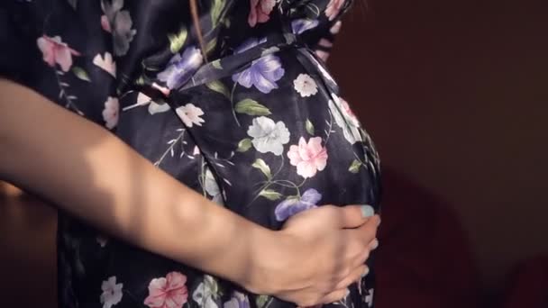 En gravid ung flicka i en siden mantel noggrant och kärleksfullt strök magen — Stockvideo