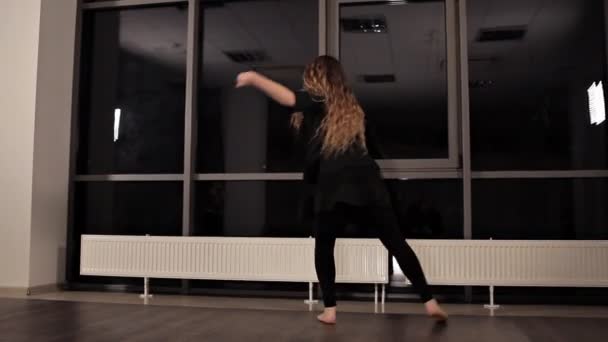 Mladá, velmi výrazná dívka tančí. Model s dlouhými vlasy hýbe tělem ve studiu — Stock video
