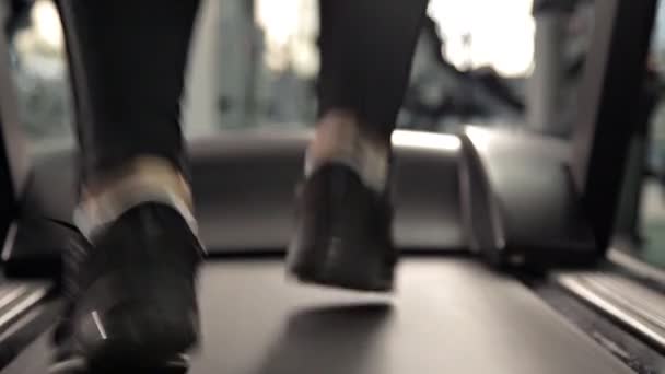 Close-up of foot sneakers fitness running on treadmill, muscular legs in gym — Stock Video