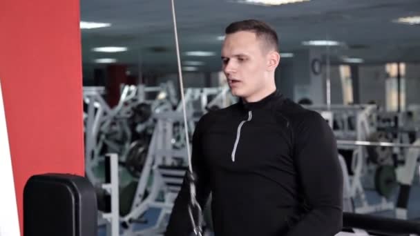 Αθλητικός νέος άνθρωπος κάνει ασκήσεις για τους μύες των χεριών και των ώμων στη μηχανή προσομοιωτή — Αρχείο Βίντεο