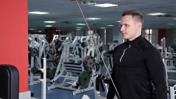 Atletische jonge man doet oefeningen voor de spieren van de armen en schouders op Simulator machine — Stockvideo