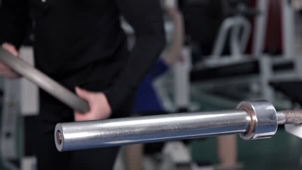 Een man verhoogt de bar werken in de sportschool — Stockvideo