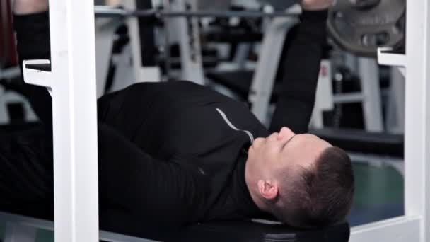 Mężczyzna podnosi bar pracujący w siłowni — Wideo stockowe