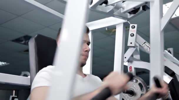 Un joven flexionando los músculos del pecho en el simulador. Salud, deporte — Vídeos de Stock