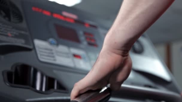 Een man neemt een langzame wandeling op de loopband in de sportschool en controleert de beeldscherm console — Stockvideo