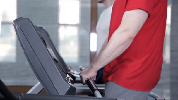 Män går långsamt på löpbandet i gymmet — Stockvideo