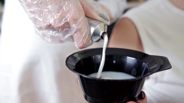 Un peluquero mezclando un tinte para el cabello en un tazón, preparar la pintura para el cabello — Vídeos de Stock