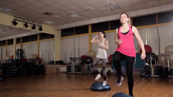 Mujer entrenadora atlética haciendo clase aeróbica con pasos a la gente grupo en un gimnasio. Concepto de deporte y salud — Vídeos de Stock