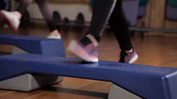 Mujer entrenadora atlética haciendo clase aeróbica con pasos a la gente grupo en un gimnasio. Concepto de deporte y salud — Vídeo de stock