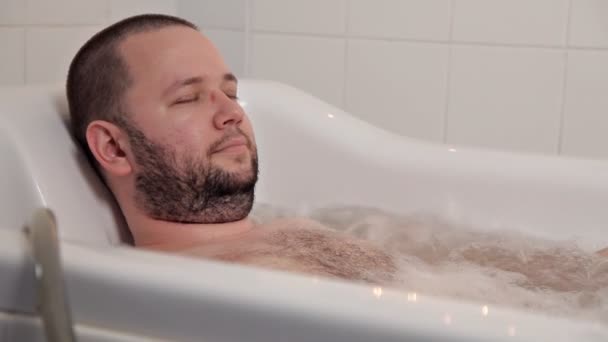 Uma pessoa relaxando em um salão de beleza. O homem está na casa de banho com hidromassagem e óleos de cura. Saúde, beleza — Vídeo de Stock
