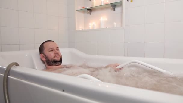 Uma pessoa relaxando em um salão de beleza. O homem está na casa de banho com hidromassagem e óleos de cura. Saúde, beleza — Vídeo de Stock