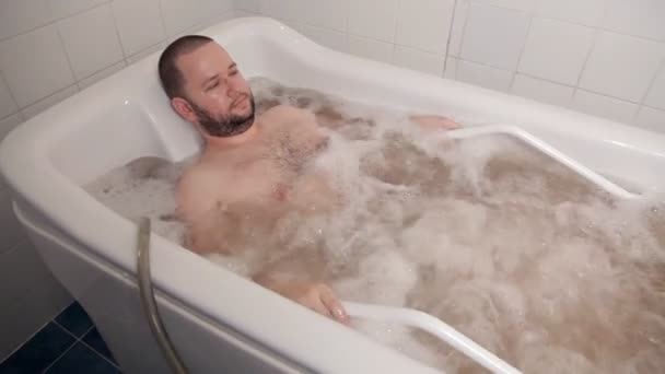 Een persoon ontspannen in een schoonheidssalon. De man ligt in de badkamer met hydromassage en helende oliën. Gezondheid, schoonheid — Stockvideo