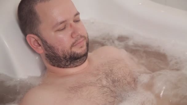 El hombre se encuentra en un baño terapéutico caliente con hidromasaje. Hotel spa — Vídeo de stock