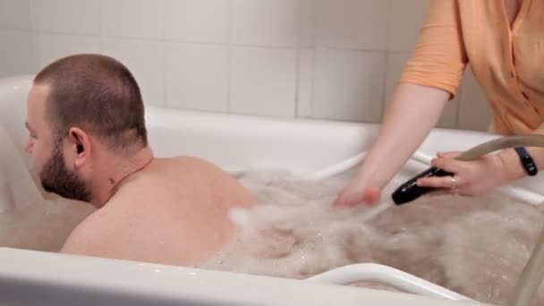 Ein Mann sitzt in einem medizinischen Badeöl, ein Mädchen in einem Wellnessbereich und lässt sich mit heißem Wasser massieren, einer speziellen Technik, einem heißen Wasserstrahl — Stockvideo