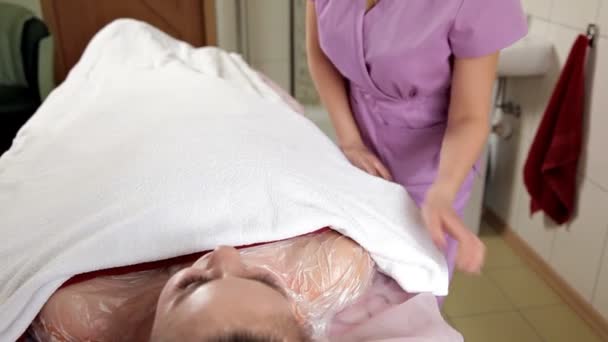 Ça fait partie du repos. Une femme calme et rêveuse s'allonge sur une serviette avec un masque crème sur le corps. Spa, voiture peau — Video