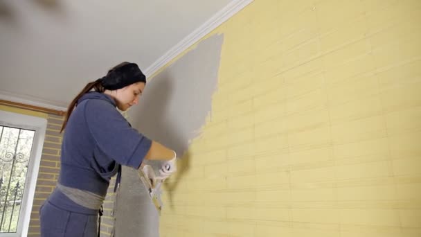 Reconstruction of the house,construction of a Young woman putty walls of the house in the apartment before painting the window — Stock Video