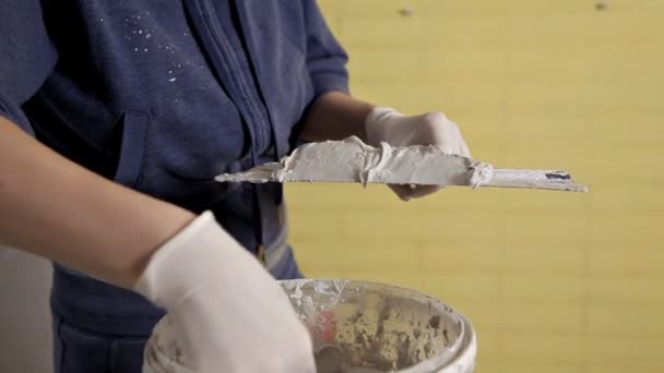 Ung flicka får kittlig pasta från en hink på en spatel. Reparation i hemmet — Stockvideo