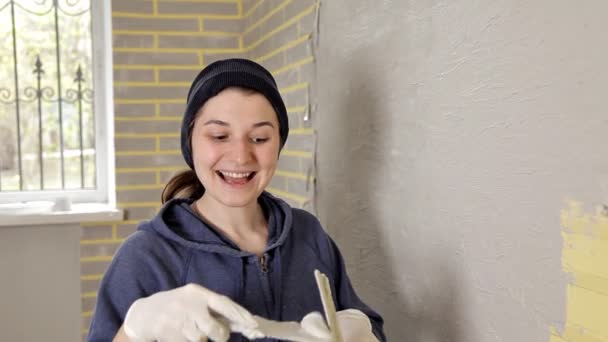 Feliz chica sonriente sosteniendo espátula y haciendo reparaciones en su apartamento — Vídeo de stock