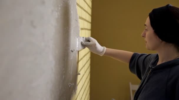 Chica con guantes blancos pone una pared en frente de la reparación. Espátula, yeso. Paredes lisas — Vídeo de stock