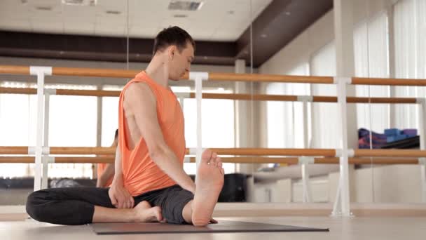 Um jovem desportista está envolvido em Ashtanga ioga no Estúdio, com um piso de madeira e grandes espelhos. Liberdade, saúde e ioga — Vídeo de Stock