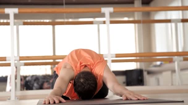 Um jovem desportista está envolvido em Ashtanga ioga no Estúdio, com um piso de madeira e grandes espelhos. Liberdade, saúde e ioga — Vídeo de Stock