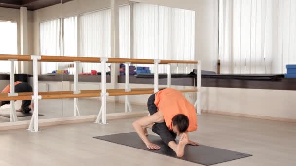 Молода спортивна людина займається в Аштанга йога в студії, з дерев'яною підлогою і великими дзеркал. Свобода, здоров'я та йога — стокове відео