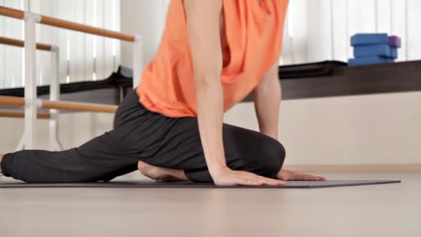 Atleta-hombre hace giros de torso, sentado en el suelo en el gimnasio, ejercicios de yoga. Salud, vida, flexibilidad — Vídeo de stock