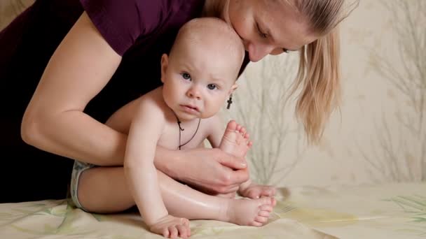 婴儿正在做的按摩服务由按摩师在按摩室与油在床上。儿童人工治疗。母亲. — 图库视频影像