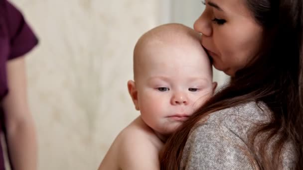 若い専門家マッサージ師は、彼女の母親の腕にある赤ちゃんに背中のマッサージを行います。子供の健康 — ストック動画